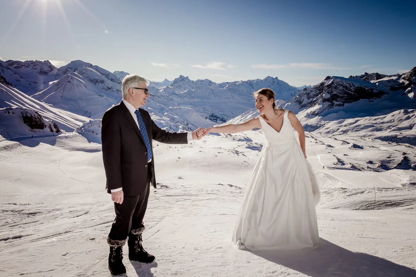 Brautpaar tanzt im Schnee auf dem Berggipfel, Winterhochzeit am Arlberg