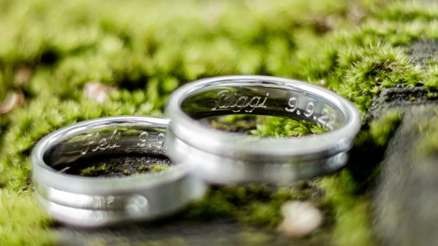 Gravierte Trauringe auf grünem Moos, Detail einer Hochzeit in der Natur