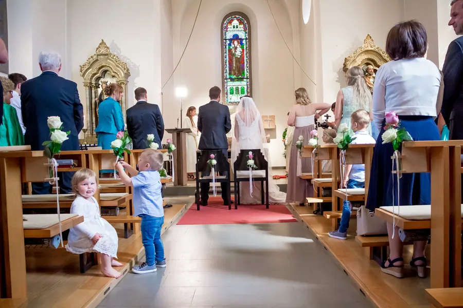Kinder mit Rosen blicken zur Kamera während der kirchlichen Trauung in Vorarlberg